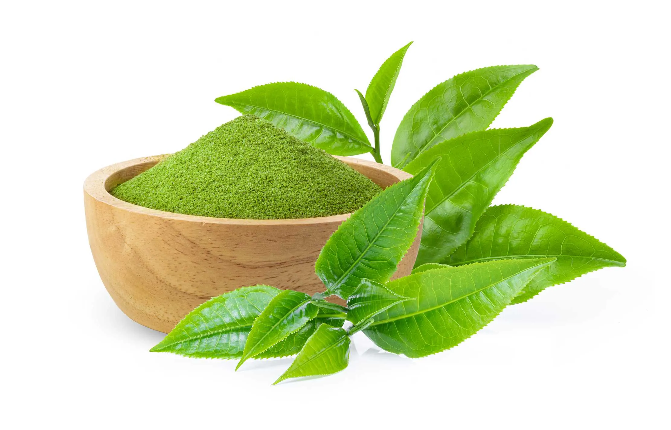 Powdered matcha green tea in a wooden bowl with a fresh tea leaf — a concentrated form of green tea used in Japanese tea ceremony